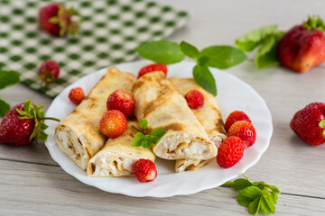 Delicious pancakes with strawberries and soft cottage cheese on a wooden table