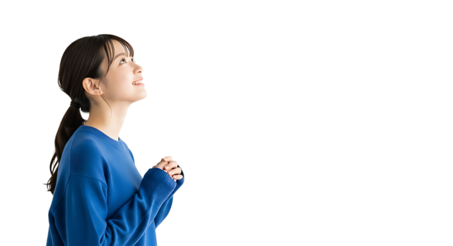 Optimistic young Asian woman looks up with hands clasped on a white background. Side profile studio shot symbolizing hope, prayer, future aspiration, gratitude, and positive thinking