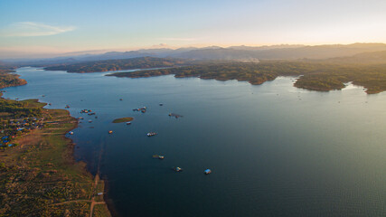 stunning aerial scene captures the meeting point of rugged mountains and endless lake. With vibrant cloudscapes and scattered islands, Vajiralongkorn Dam stands as a symbol of Thailand’s harmony