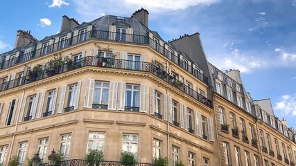 Facade of beautiful historic buildings and blue sky with clouds on a sunny day in Paris, France.