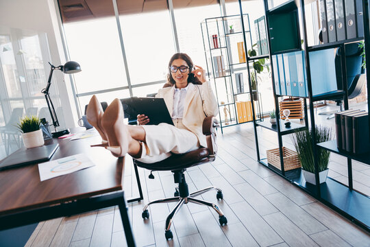 Confident businesswoman relaxing at office desk in stylish workspace with formal attire showcasing professional demeanor - Powered by Adobe