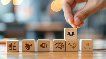 Wooden blocks with psychology and mental health symbols arranged by hand showing brain, palm, and human icons. Concept for psychological therapy and counseling