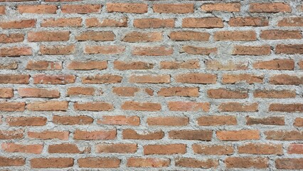 The fence is made of red and orange bricks. The old brick fence has stains and cracks. Old and aged...