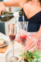 Pouring Bubbly over Frozen Berries in Champagne Flutes