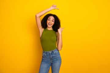 Portrait of a young cheerful woman in casual clothing with a vibrant yellow background, showcasing...