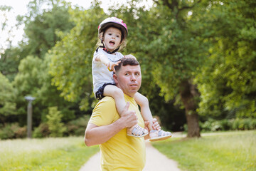 The father holds the child on his shoulders.