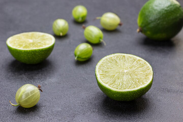 Lime halves and gooseberry berries on black background.