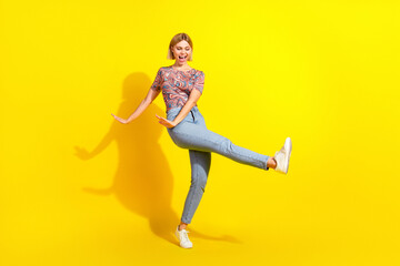 Young stylish woman with a pleasing expression posing playfully against a bright yellow background...