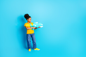 Happy young girl holding a water gun with vibrant expression on a bright blue background portraying cheerful leisure