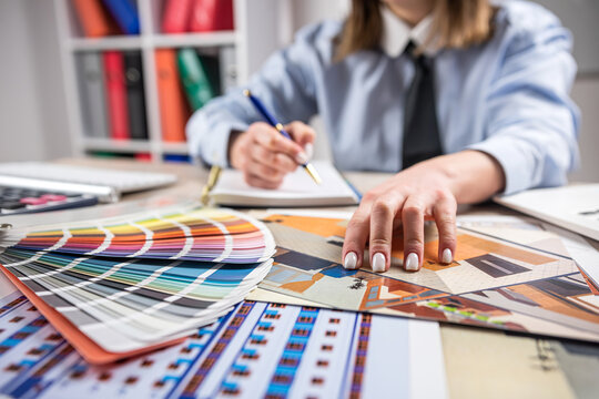 Female designer at creative work with blueprints and color set samples - Powered by Adobe