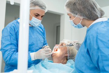 man dentists and female nurse examine the mouth of young elderly woman. Reception at dentist...