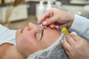 beautician doing manual face cleansing by young female client in beauty studio