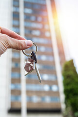 Real Estate Deal: Hand Holding Apartment Keys in Front of Modern Building