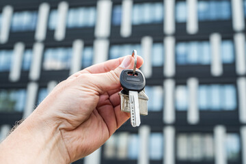 Business Lease Concept: Hand Holding Keys in Front of Office Building