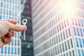 Keys in Hand Against Modern Office Skyscrapers – Real Estate and Investment Concept.  Perfect for business  real estate finance and architecture-related visuals.