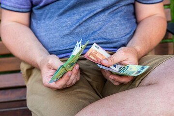 Man Holding Euro Banknotes in Wallet – Personal Budget and Finance Concept. Close-up image of a man holding a black leather wallet with visible euro banknotes