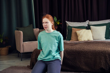 Young person expresses emotions while seated in a bedroom with cozy decor and subdued lighting