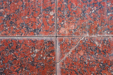Rustic red granite surface with visible cracks and a textured pattern, perfect for backgrounds or design projects needing a vintage touch. Photo. High resolution