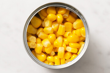 Canned sweet corn in metal tin. Bright yellow kernels on white background. Preserved vegetable close-up. Healthy food ingredient for salads, soups or side dishes. Convenient kitchen staple