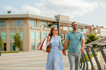 Couple enjoys a sunny day walking hand in hand along a modern shopping district promenade
