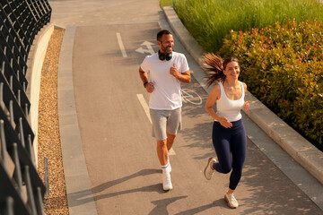 Running together along a peaceful path surrounded by greenery in the bright morning sun