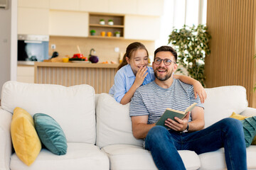 Father and daughter share a joyful reading moment in a cozy living room