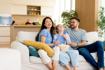 Family enjoying a cozy movie night at home with popcorn and laughter in a bright living room setting