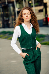 Confident young businesswoman in a stylish green waistcoat outdoors on a sunny day in the city,...
