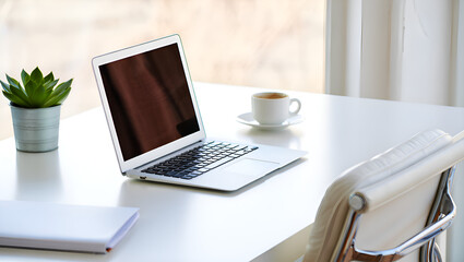 Fototapeta premium Clean White Desk Setup with Laptop, Coffee, and Succulent Plant near a Window in Bright Natural Light