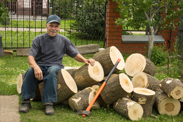 Elderly active man in prepares firewood. He is pleased and cheerful.