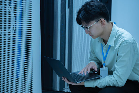 Computer engineer is setting up network in server room,Systems Maintenance Technician,Male engineer working in server room at modern data center