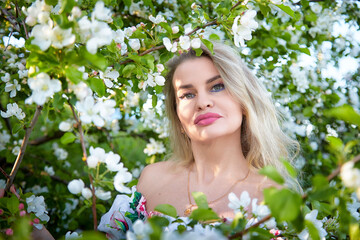 Fototapeta premium Blonde middle-aged woman captures a selfie in a blooming garden surrounded by white flowers