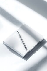 White notebook with pen, and sunlight.