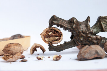 Close side view of metal nutcracker dragon with half of open walnut and box with inshell walnuts...