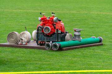 Firefighting pump and rolled fire hoses arranged on the grass – competition setup ready for a...