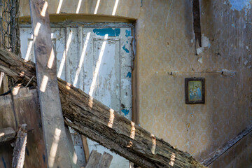 Collapsed interior of an abandoned house with a damaged window and old wallpaper – a faded...