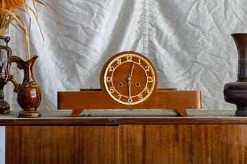 Vintage wooden mantel clock from the communist era, placed on a sideboard and surrounded by...