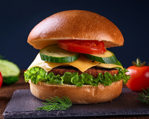 Isolated cheeseburger with fresh vegetables on a black background