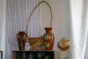 Brown vintage vases, a wicker basket, and a wooden sailing ship model arranged on a sideboard – retro-style decor from the communist era.