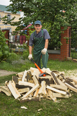 Elderly active man in prepares firewood for heating a bathhouse. He is pleased