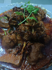 Rich and spicy Indian-style mutton curry served with a topping of fried onions and fresh coriander leaves. Perfect for traditional cuisine or food presentation concepts.
