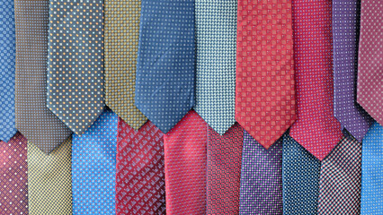 Row of ties with different colors and patterns. Some are blue, some are red, and some are purple