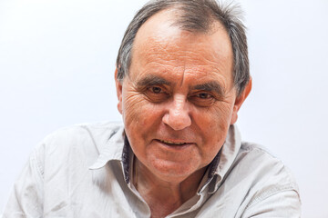 Elderly caucasian male with gray hair smiling in a white shirt