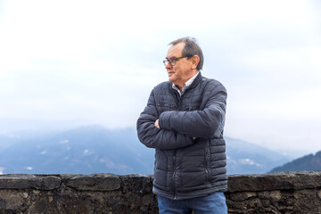 Mature caucasian male posing thoughtfully against mountainous landscape