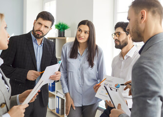 Corporate business team having a work meeting in the office. Group of young people standing...