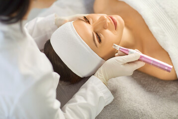 Dermatologist doctor doing cosmetology derma pen beautician procedure, mechanical female face skin...