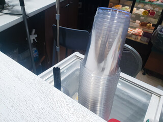 A stack of plastic cups. Disposable plastic glasses transparent, in cafe for drinks.