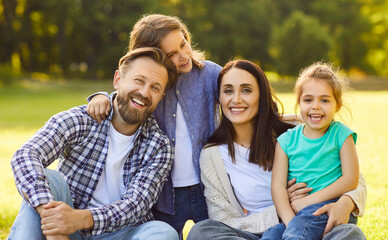 Happy family together in green summer park, outdoors posing for portrait, embracing, showing affection, closeness, friendly parents, children happiness, enjoying pleasant moment together in sunny day