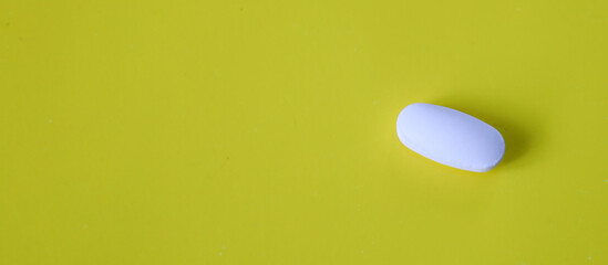 A white oval tablet positioned on a bright yellow background creates a minimalist yet expressive...