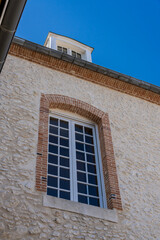 Vue sur la façade d’une belle maison ancienne baignée d’une douce lumière naturelle, mettant en valeur son architecture élégante et son charme intemporel.